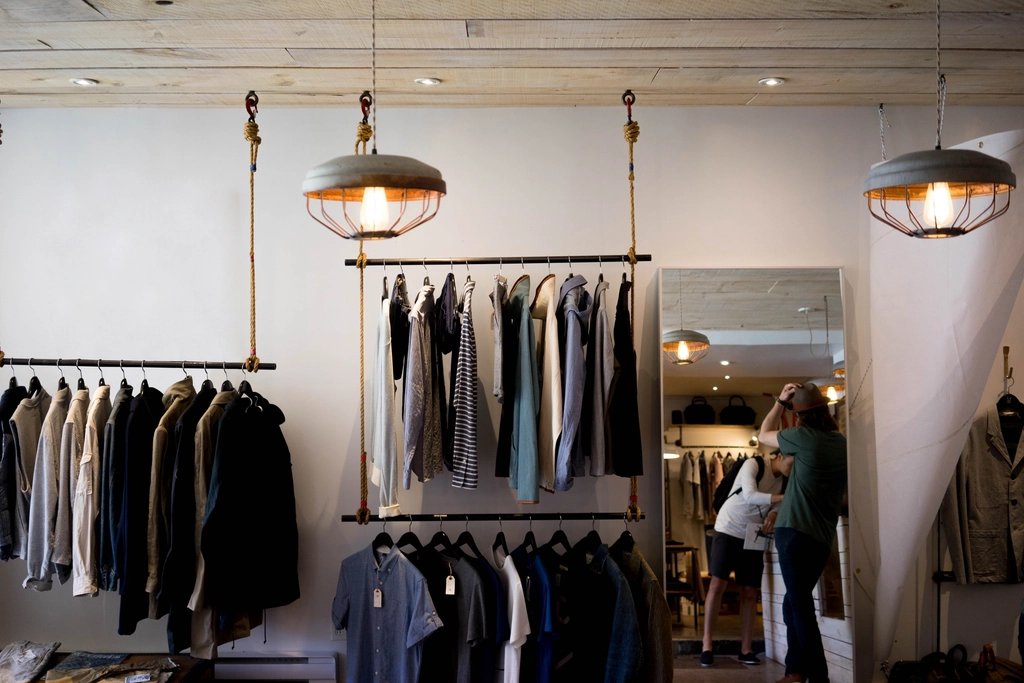 Menswear hanging on racks in a dim, warmly lit clothing store