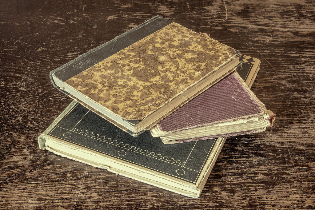 A stack of old books on a dark wooden table