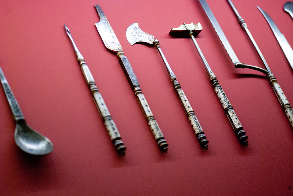 Antique surgical instruments laid out on dark red cloth