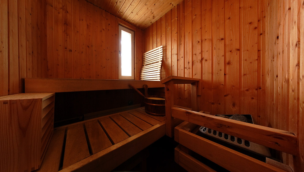 A dark wooden Finnish sauna interior with a heater