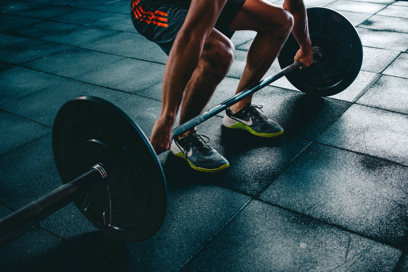 Lifter gripping a loaded barbell in a dark gym