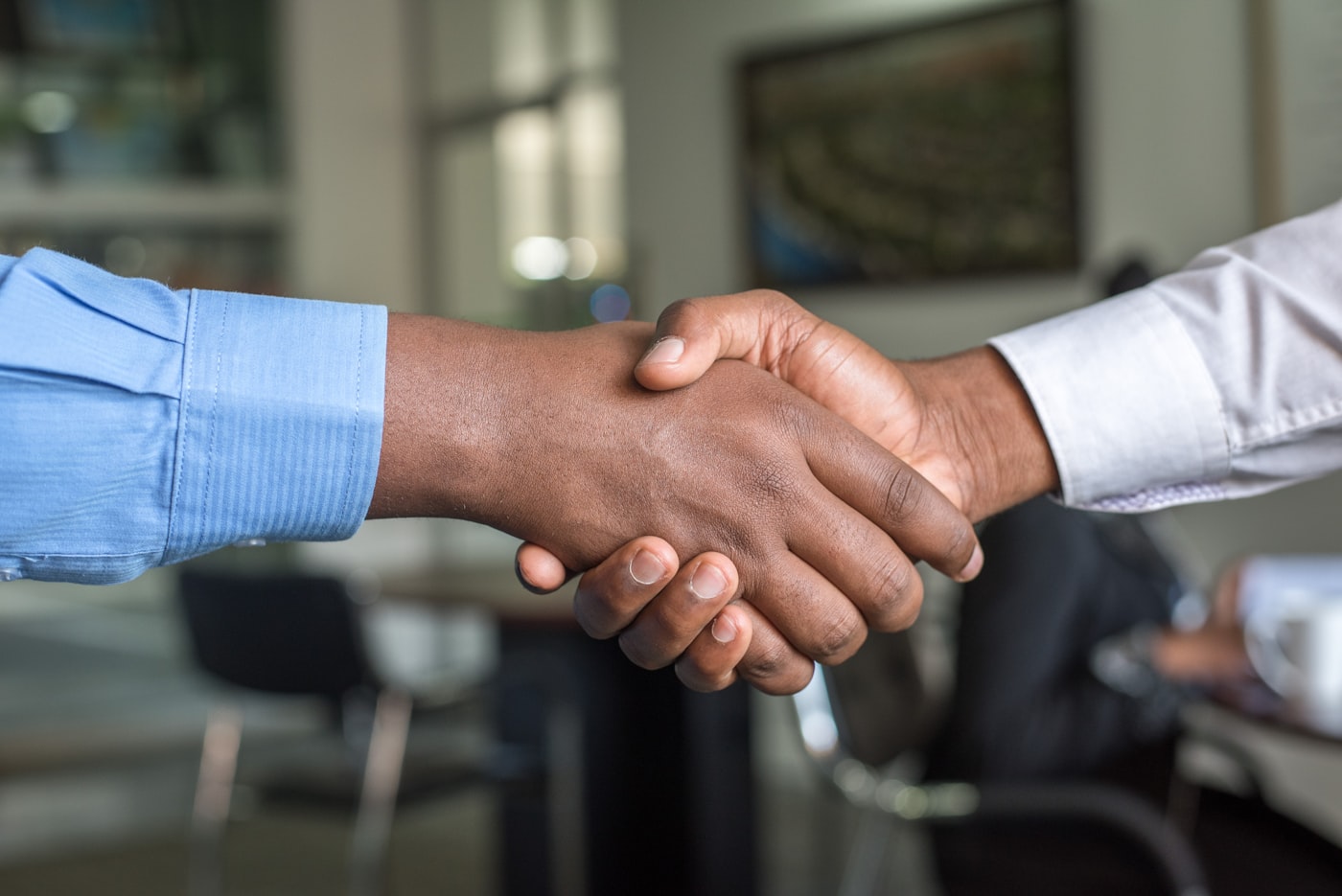 Two people shaking hands across a desk