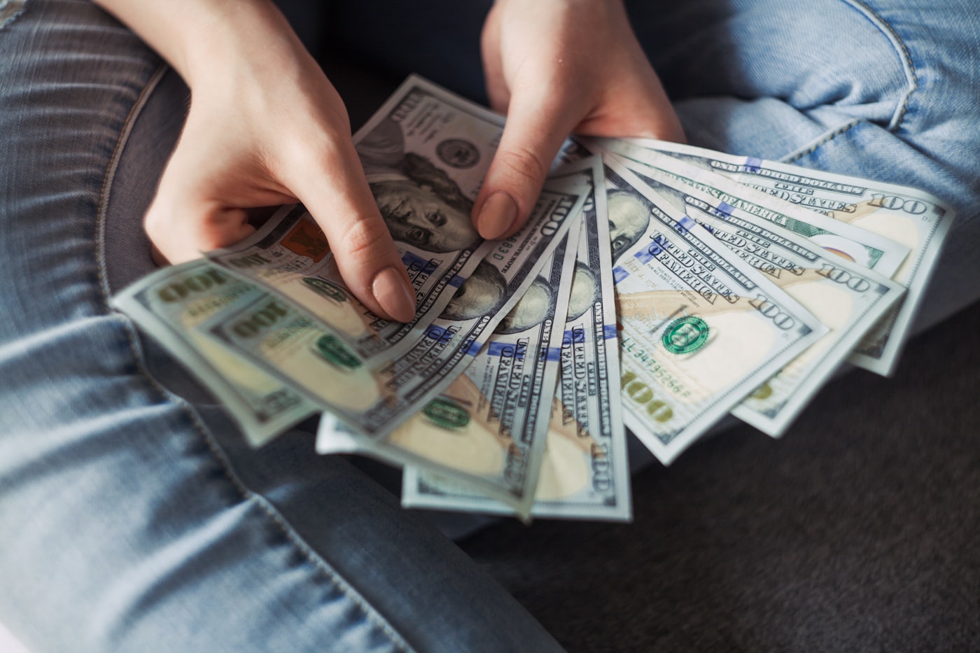 Hands counting a fan of hundred dollar bills
