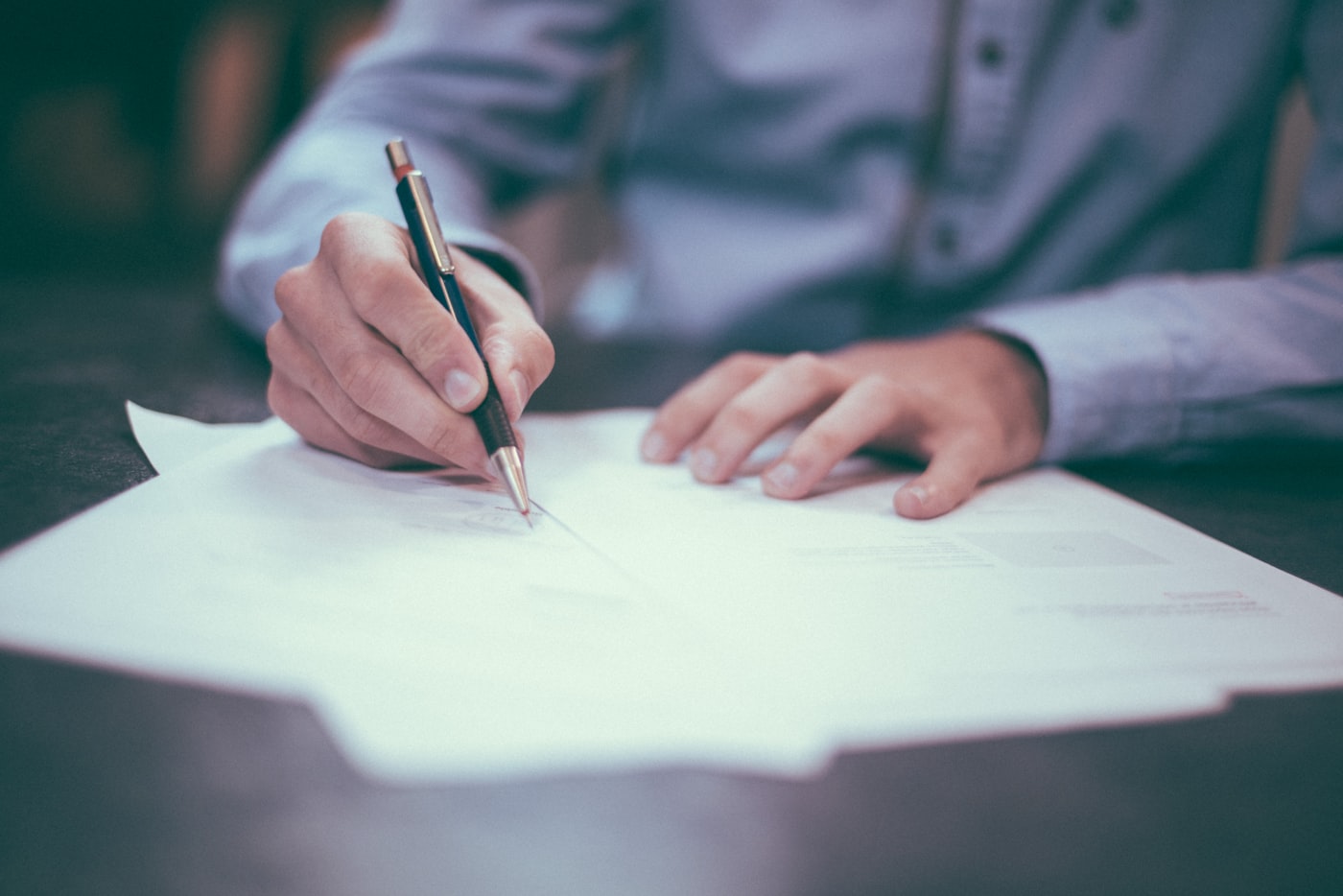 A man signing terms on paper with a pen